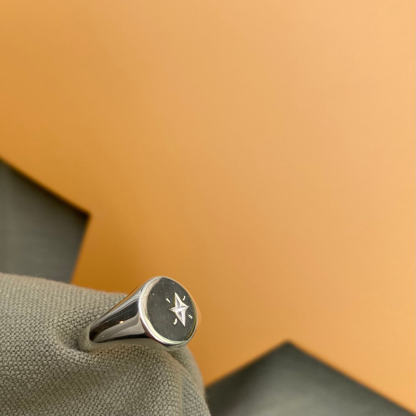 Close up of silver signet ring with a star engraved into it