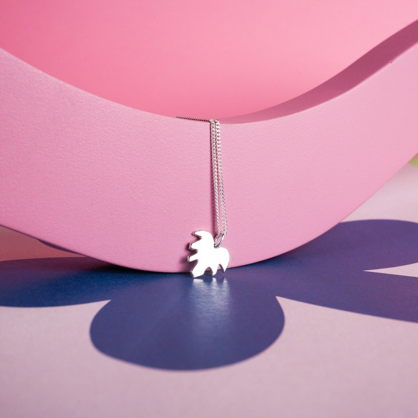 Close up of pendant necklace with a silver leaf shape charm on it