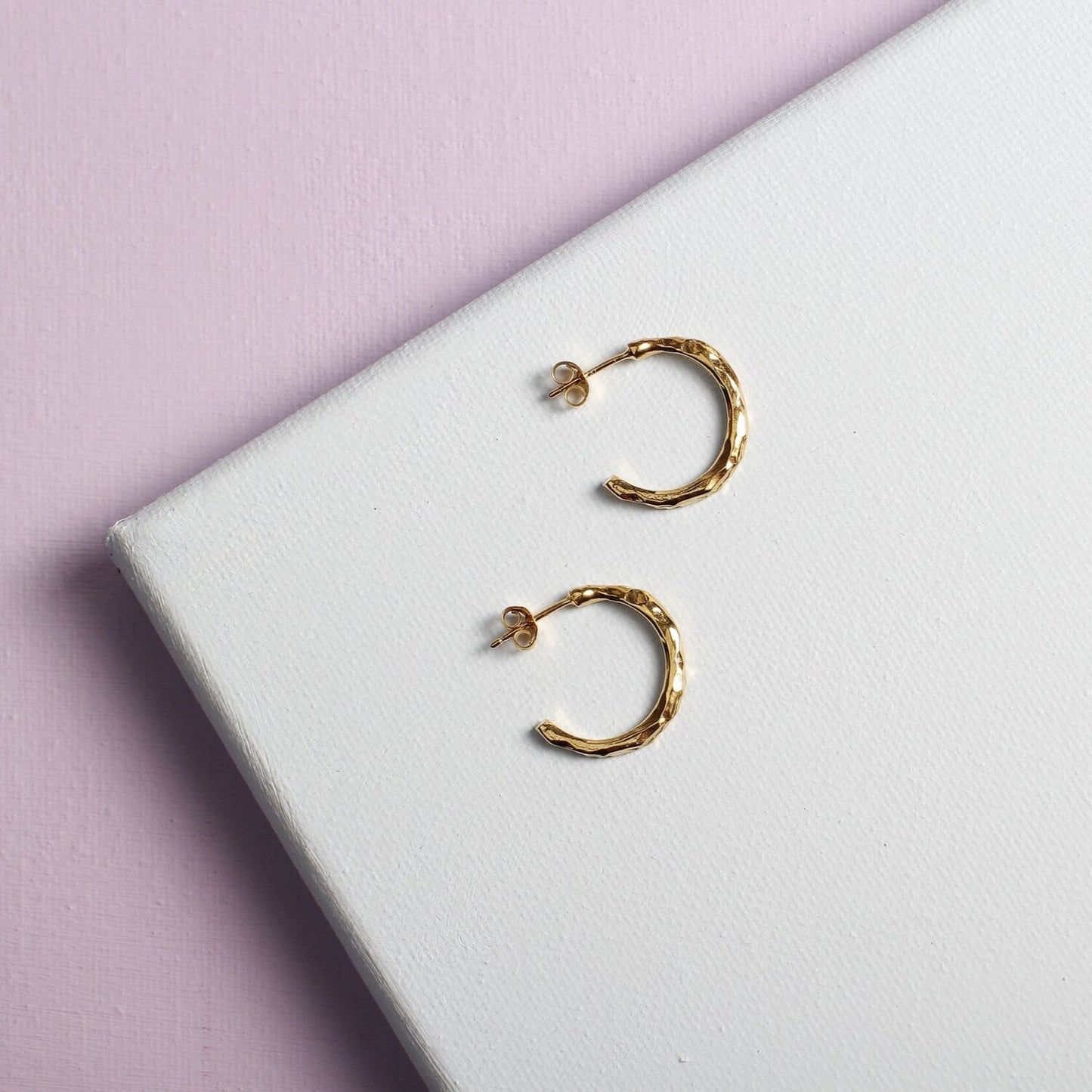 Close up of small gold hoop earrings with a textured surface