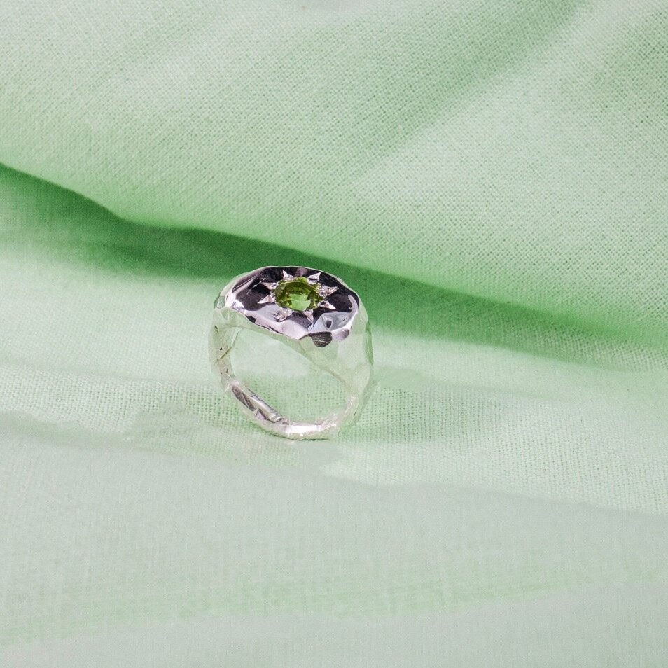 Silver signet ring with a pale green gen in the centre, surrounded by a sun shape