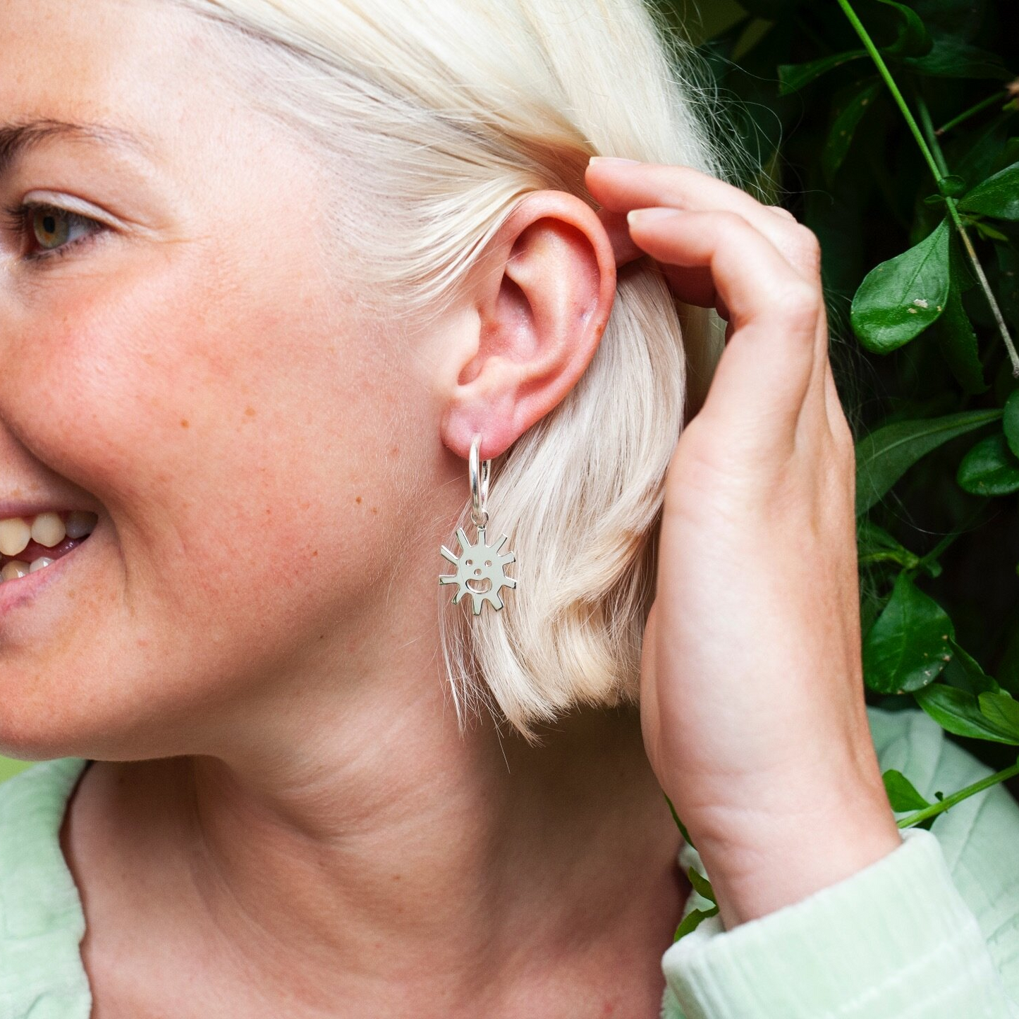 Close up of woman wearing silver Smiley Sun Hoops earring