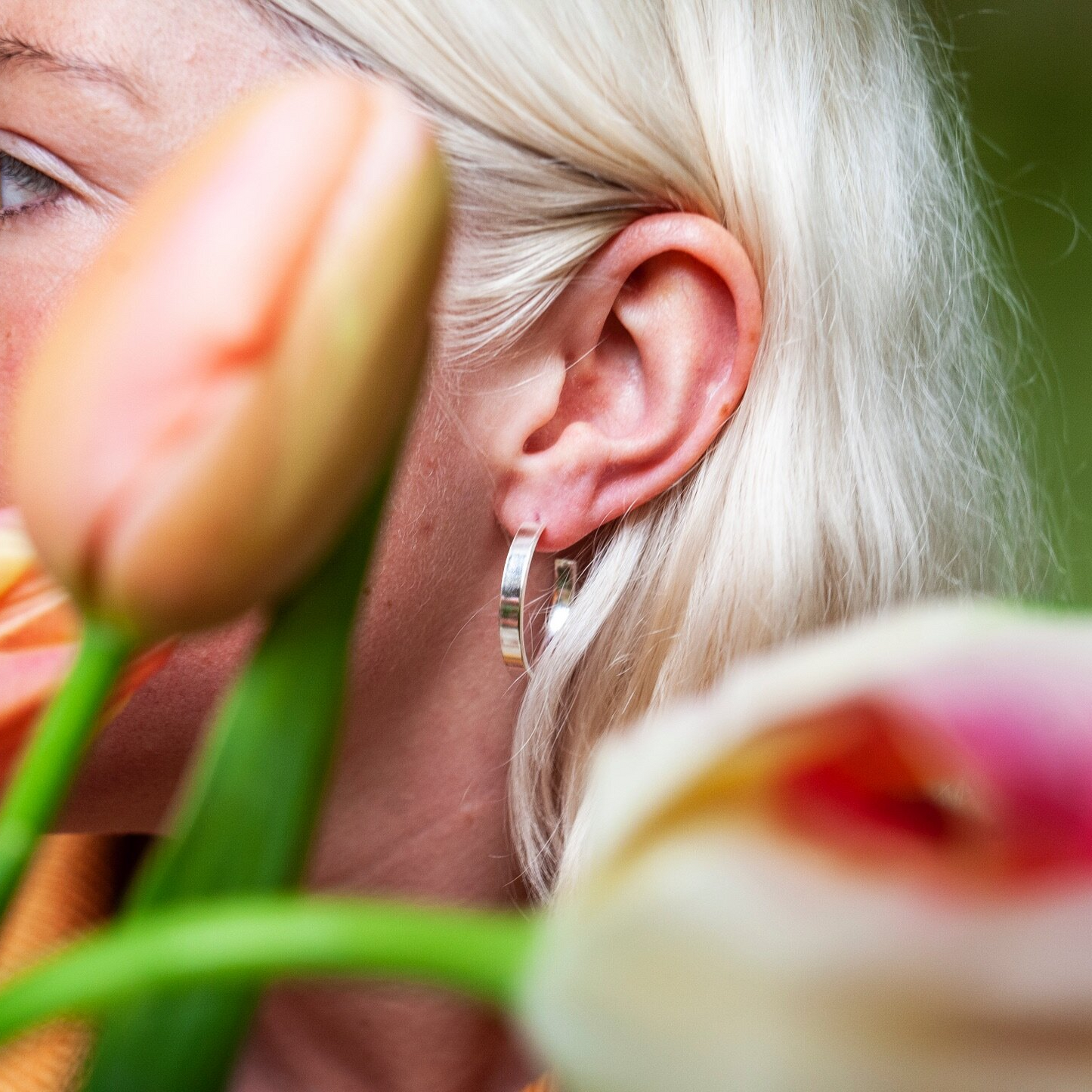 Close up of woman wearing medium size flat hoop silver earring