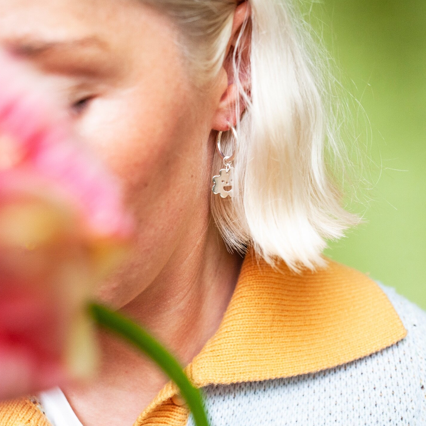 Woman wearing silver Smiley Flower Hoops earring