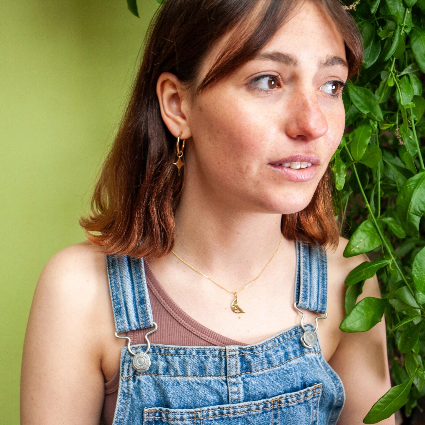 Woman wearing small gold hoop earrings with a star shaped charm 