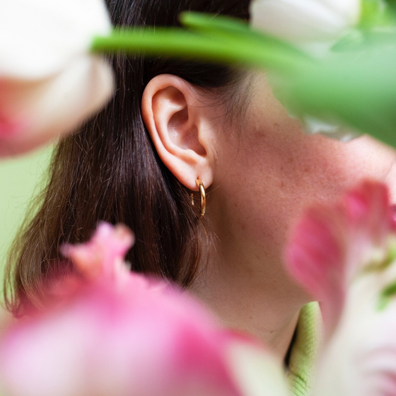 Close up of woman wearing small gold hoop earring