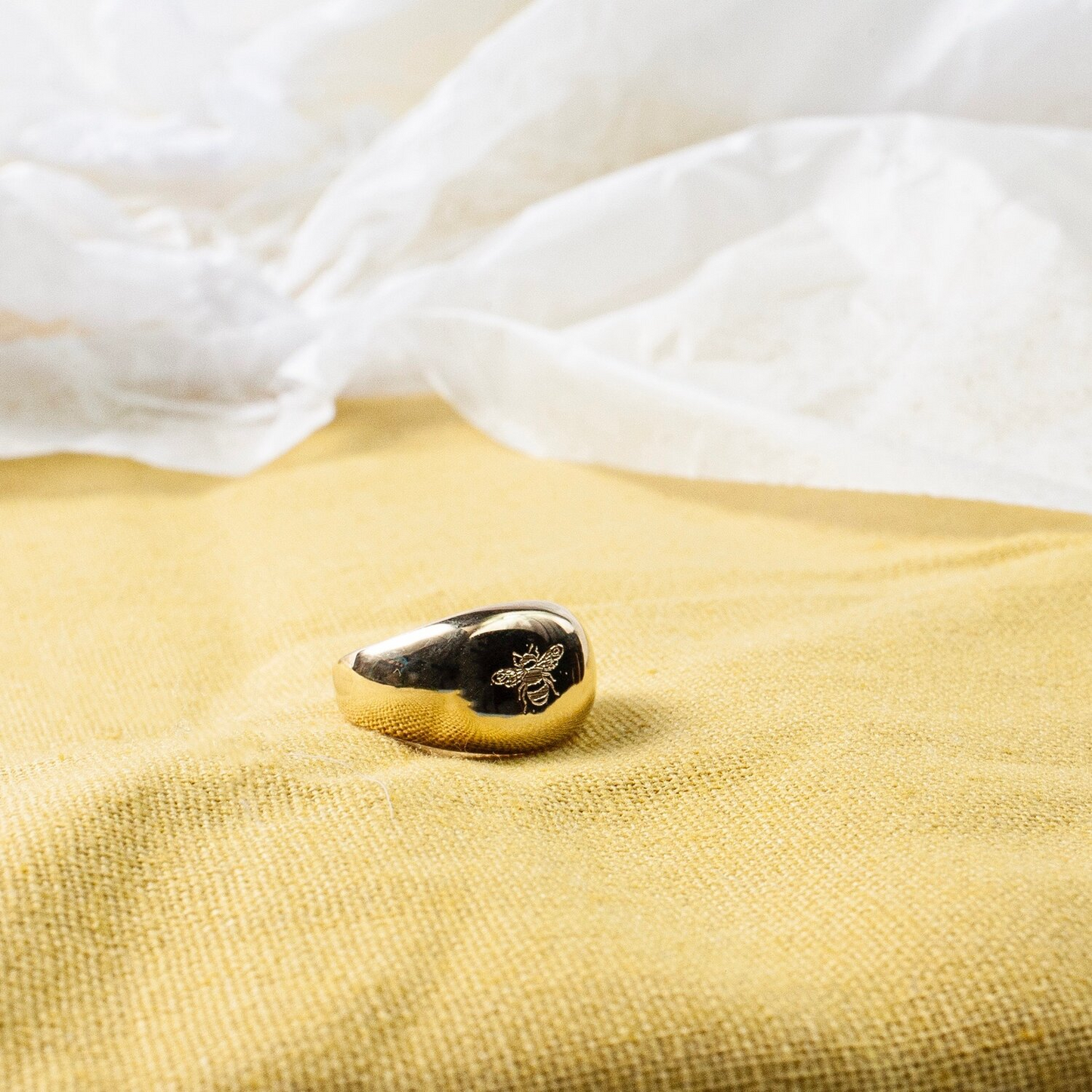 Close up of gold ring with a bee engraved into it