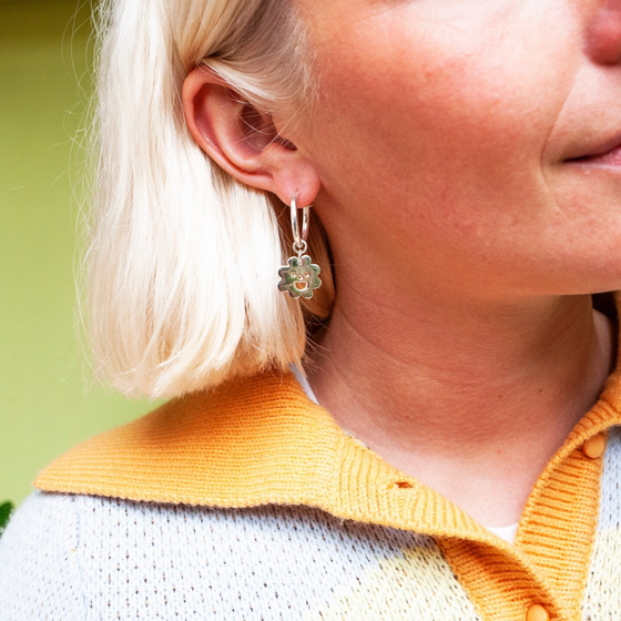 Close up of woman wearing gold Smiley Flower Hoops earring