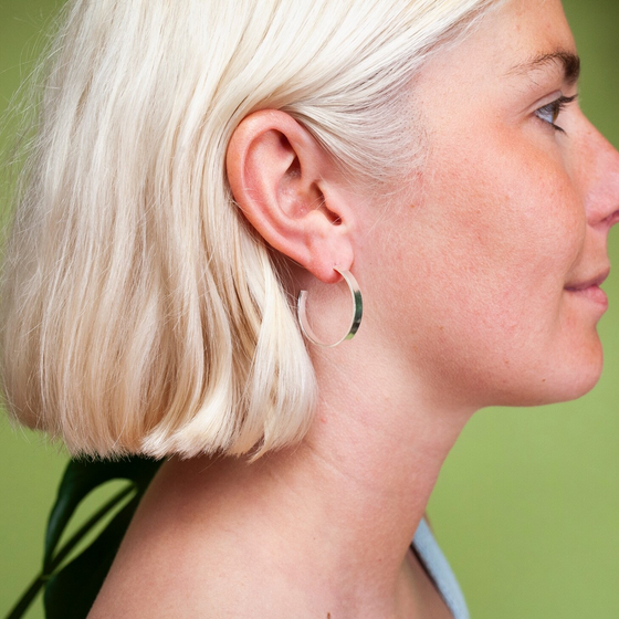 Close up of woman wearing medium size flat hoop silver earrings