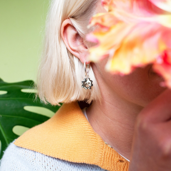 Close up of woman wearing silver Smiley Flower Hoops earring