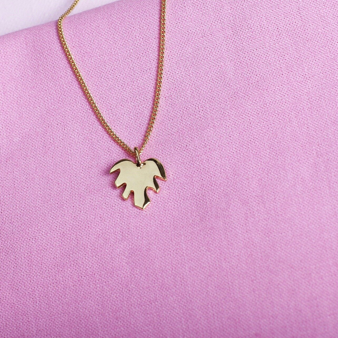 Close up of pendant necklace with a gold leaf shape charm on it