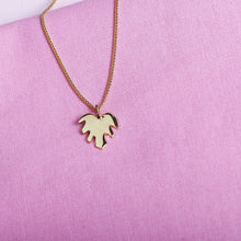  Close up of pendant necklace with a gold leaf shape charm on it