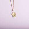 Close up of pendant necklace with a spiky irregular shaped charm with a smiley face on