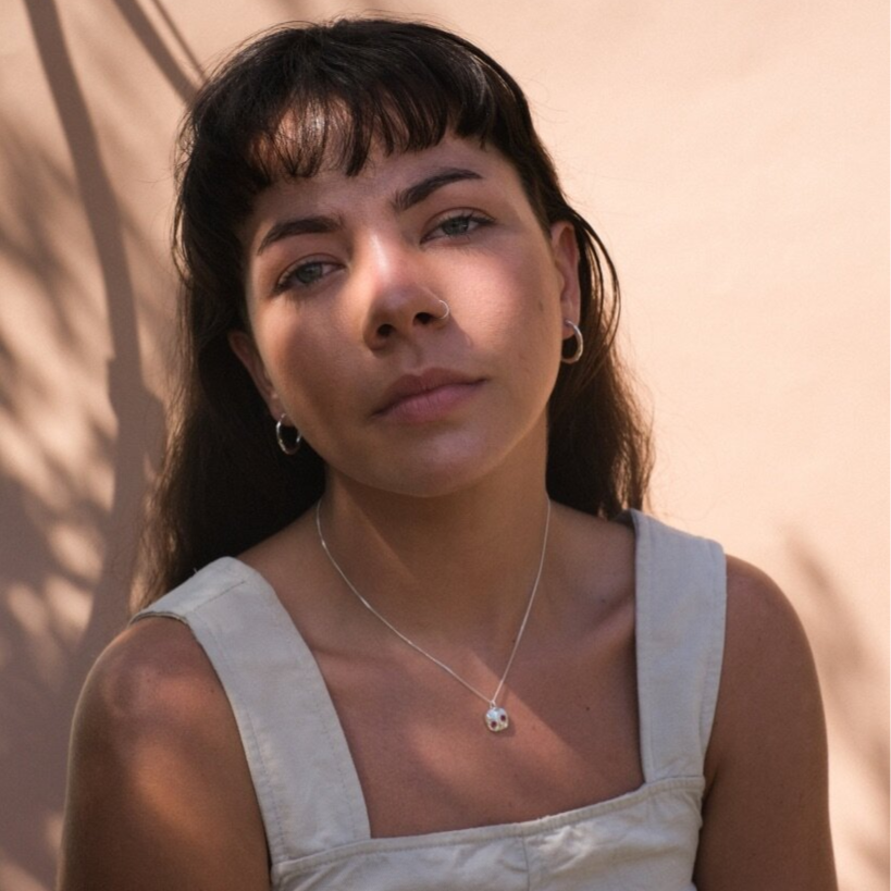 Woman wearing small gold hoop earrings with a textured surface