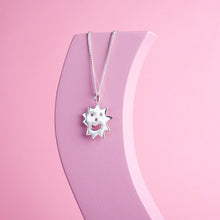  Close up of pendant necklace with a spikey irregular shaped charm with a smiley face on