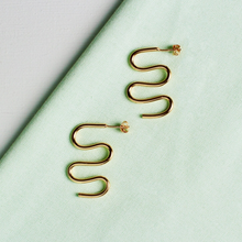  Close up of gold earrings in the shape of a squiggle