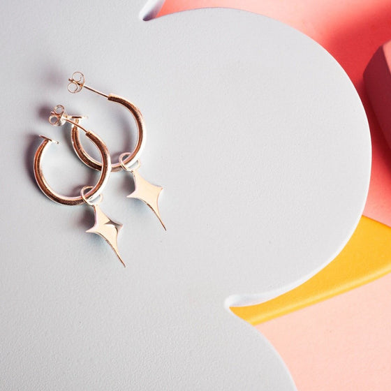 Small gold hoop earrings with a star shaped charm 