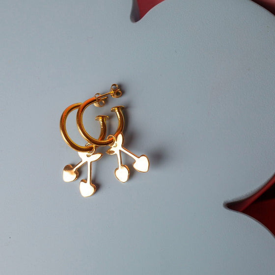 Gold hoop earrings with a cherry charm